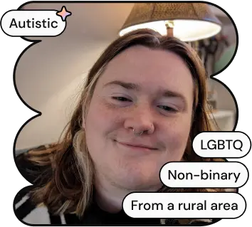 A photo of Jacob, one of ND Connect's co-founders. They are a white non-binary person with long brown hair, smiling at the camera. He is wearing a sweater with pumpkins and cartoon ghosts on it.